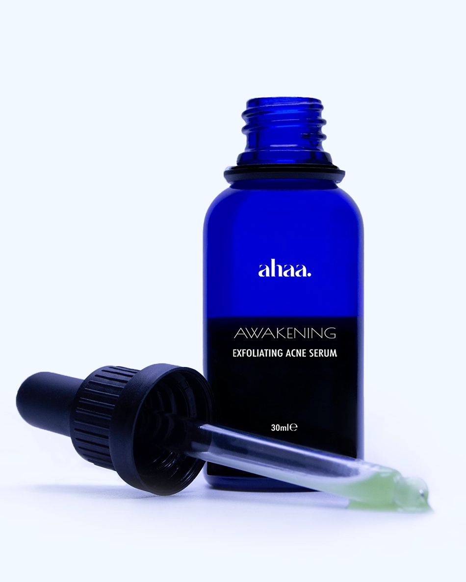 A picture showing the glass blue opened bottle of Awakening - the exfoliating acne fighting face serum by Ahaa Skincare