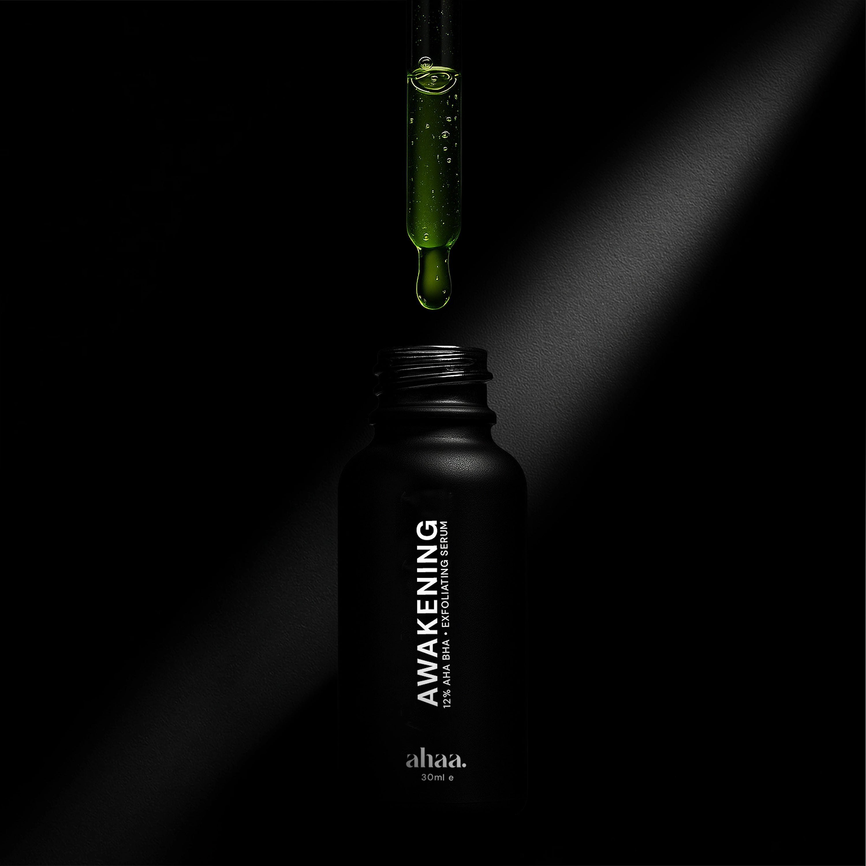 Black bottle labeled 'Awakening' with a dropper dropping green AHA and BHA liquid onto it against a dark background. 
